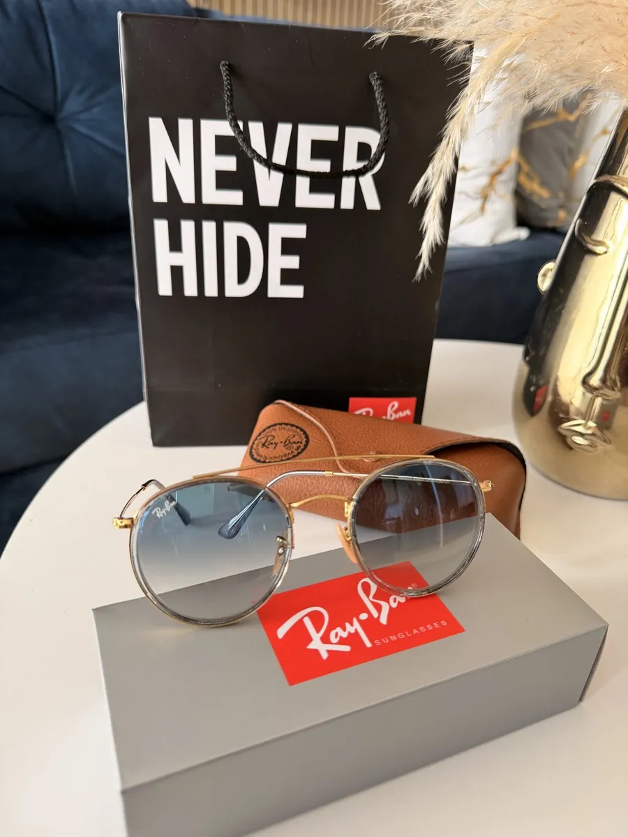 Fotografía del inventario de Aurelium: gafas de aviador doradas con lente azul degradado y estuche